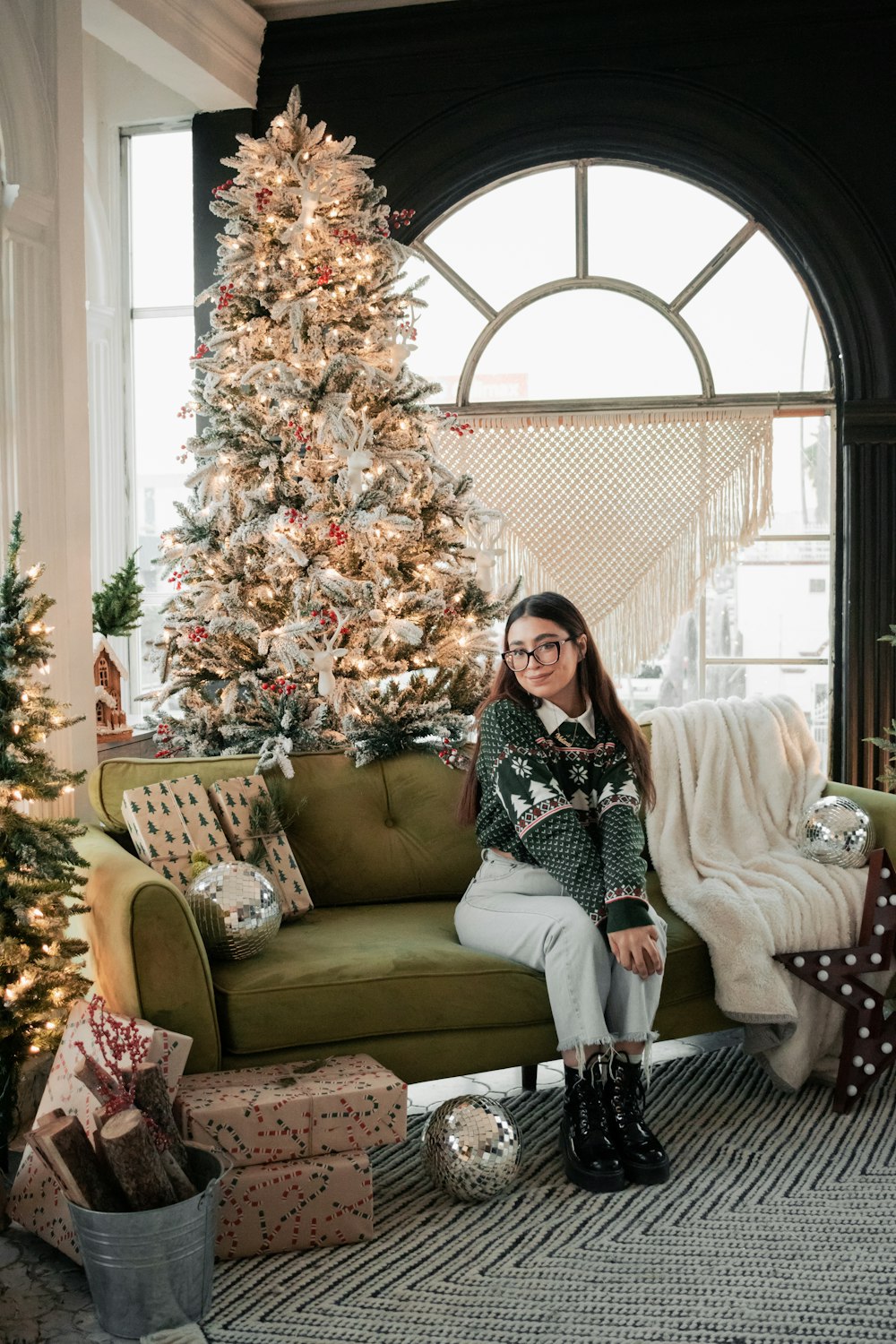 a woman sitting on a couch in front of a christmas tree
