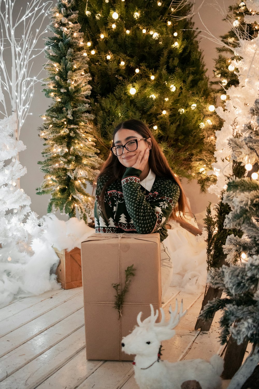 a woman sitting in a box in front of a christmas tree