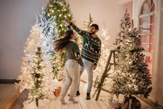 Couple dancing joyfully inside a warmly lit rustic barn decorated with string lights and wooden beams.