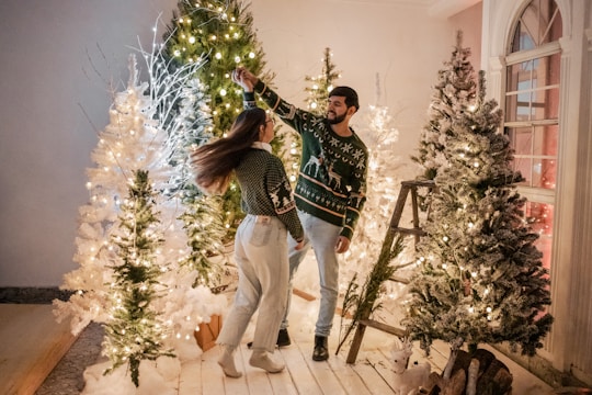 Couple dancing joyfully inside a warmly lit rustic barn decorated with string lights and wooden beams.