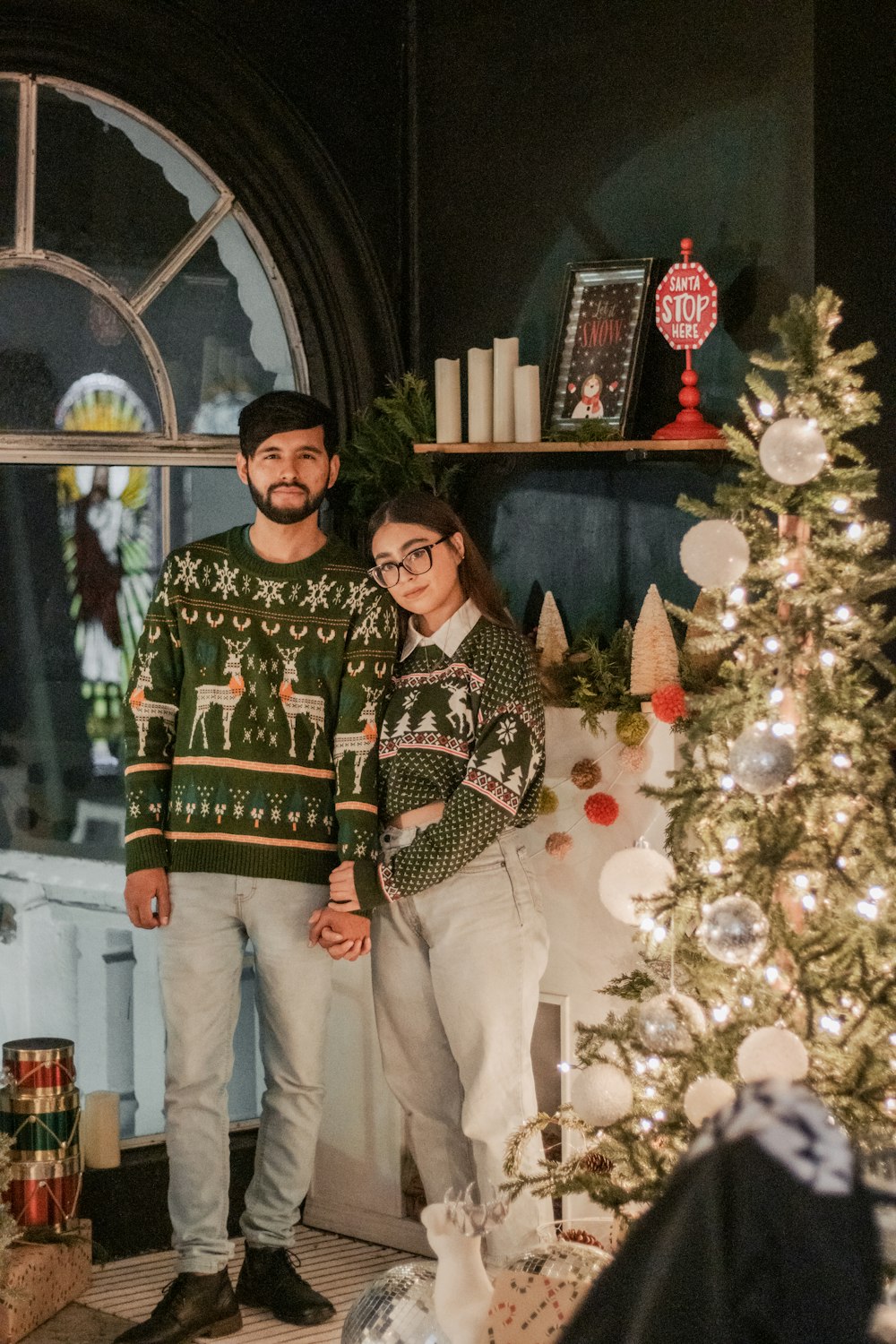 a man and woman standing next to a christmas tree