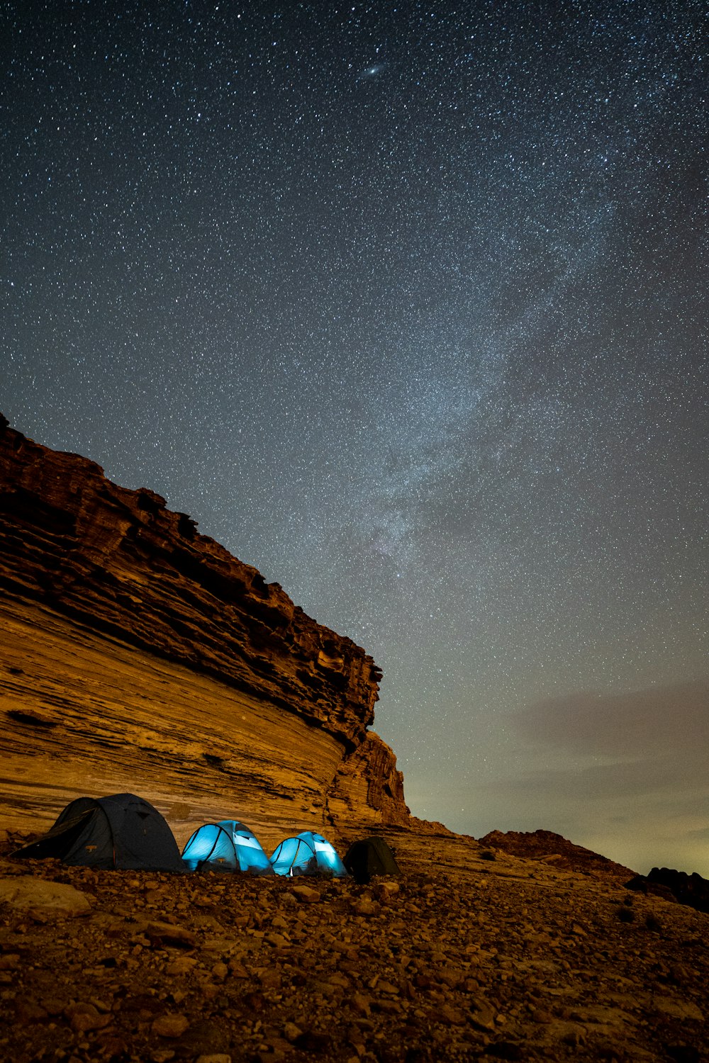 a tent and a tent in a rocky area with a starry sky above