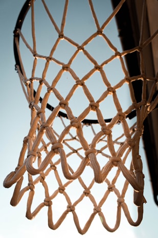 A close-up of a basketball swishing through the net with the navy and charcoal court lines visible beneath.