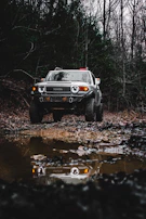 Toyota Fortuner 4x4 parked beside a calm lake reflecting sunset hues.