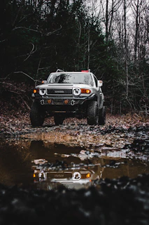 Toyota Fortuner 4x4 parked beside a calm lake reflecting sunset hues.