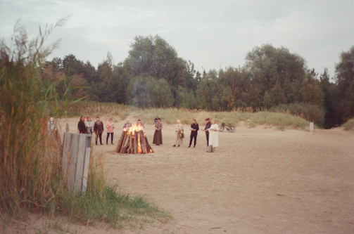 Guests laughing around a bonfire near the hostel, with scooters parked nearby.