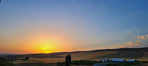 A panoramic view of a golden sunset over a premium land plot in Tangier with rolling hills.