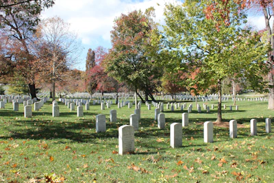 Elegant grave site with neatly arranged sage green foliage and subtle orange blossoms.