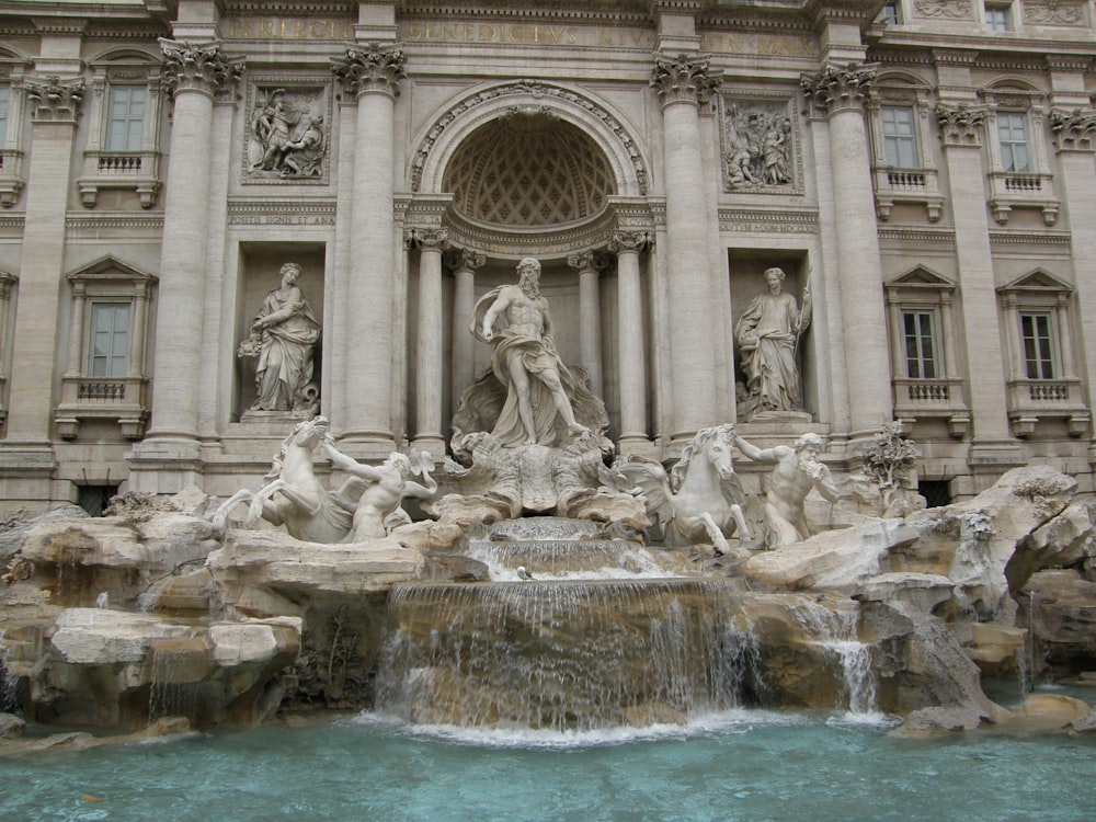 a fountain with statues in front of Trevi Fountain