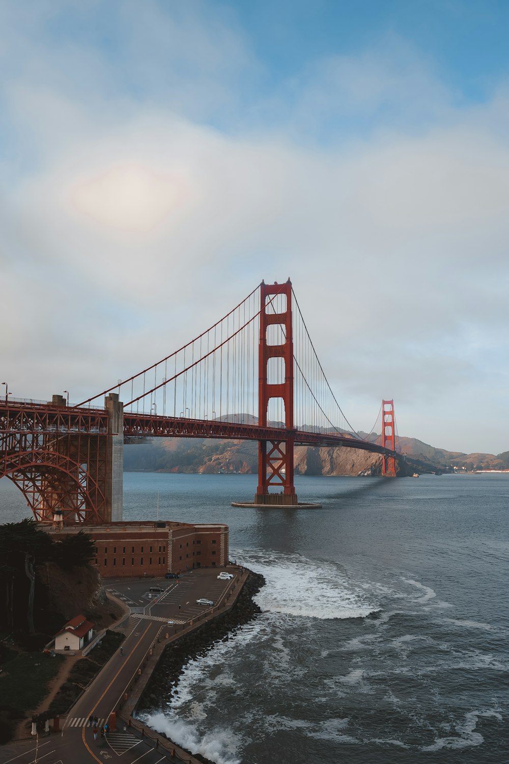 a large red bridge over water with Golden Gate Bridge in the background