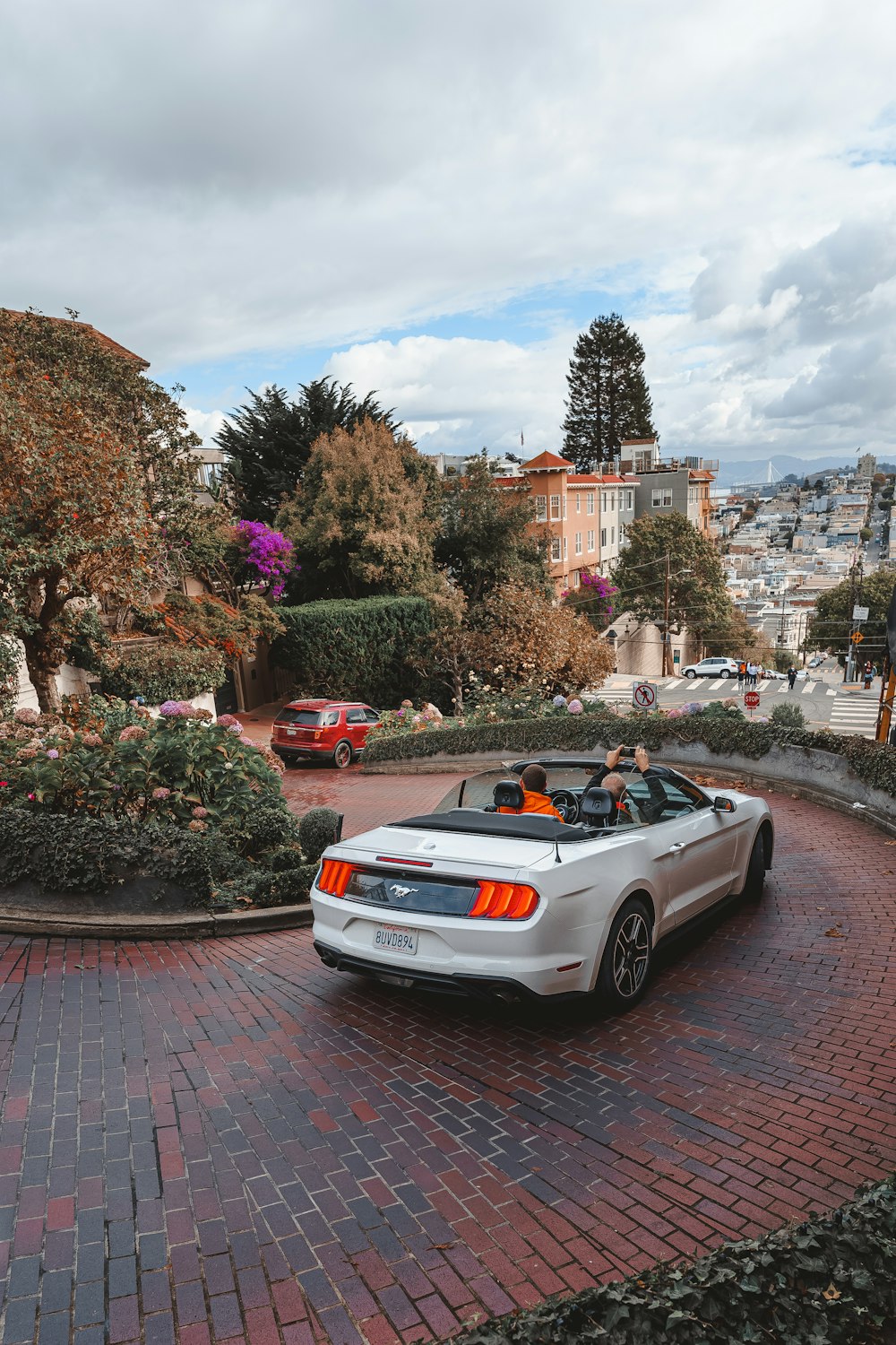 a white sports car with people in it parked on a brick road