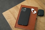Compact smartphone with a stylish case resting beside wireless earbuds