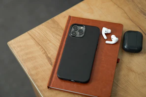 A stylish smartphone lying next to headphones and a notebook on a clean desk