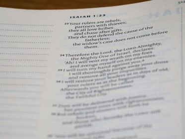 A close-up view of a page from a Bible, showcasing text from Isaiah 1:23 to 1:26. The text discusses themes of corruption, judgment, and redemption. The page includes verse numbering and is written in a serif font.