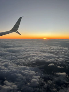 A sleek airplane soaring above fluffy clouds at sunset, symbolizing seamless travel connections.