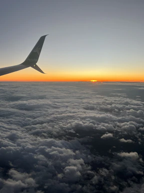 A sleek airplane soaring above fluffy clouds at sunset, symbolizing seamless travel connections.