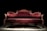 A luxurious Victorian-style sofa with elegant, deep red velvet upholstery and ornate wooden carvings. The setting is dramatically lit, highlighting the intricate textures and curves of the sofa against a dark background.