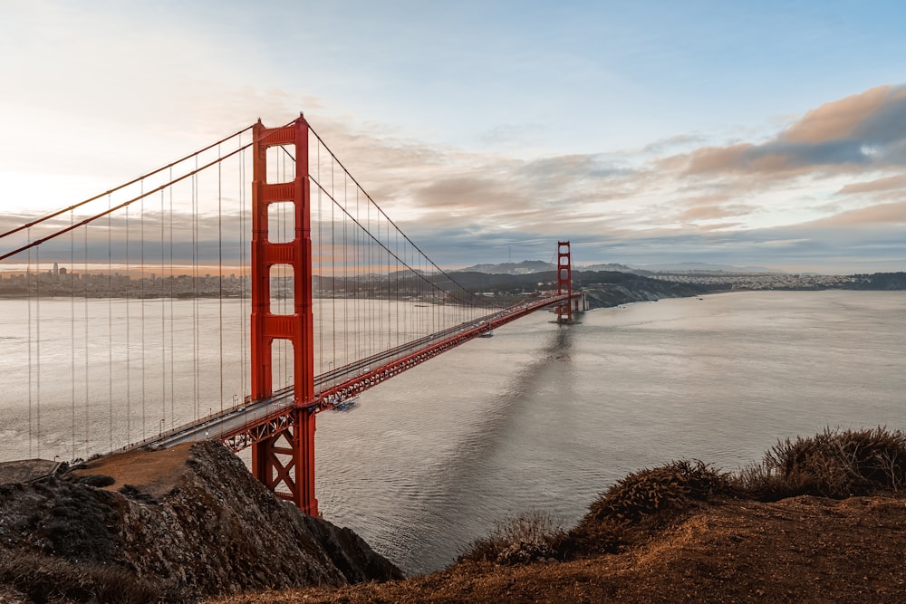 a red bridge over water with Golden Gate Bridge in the background