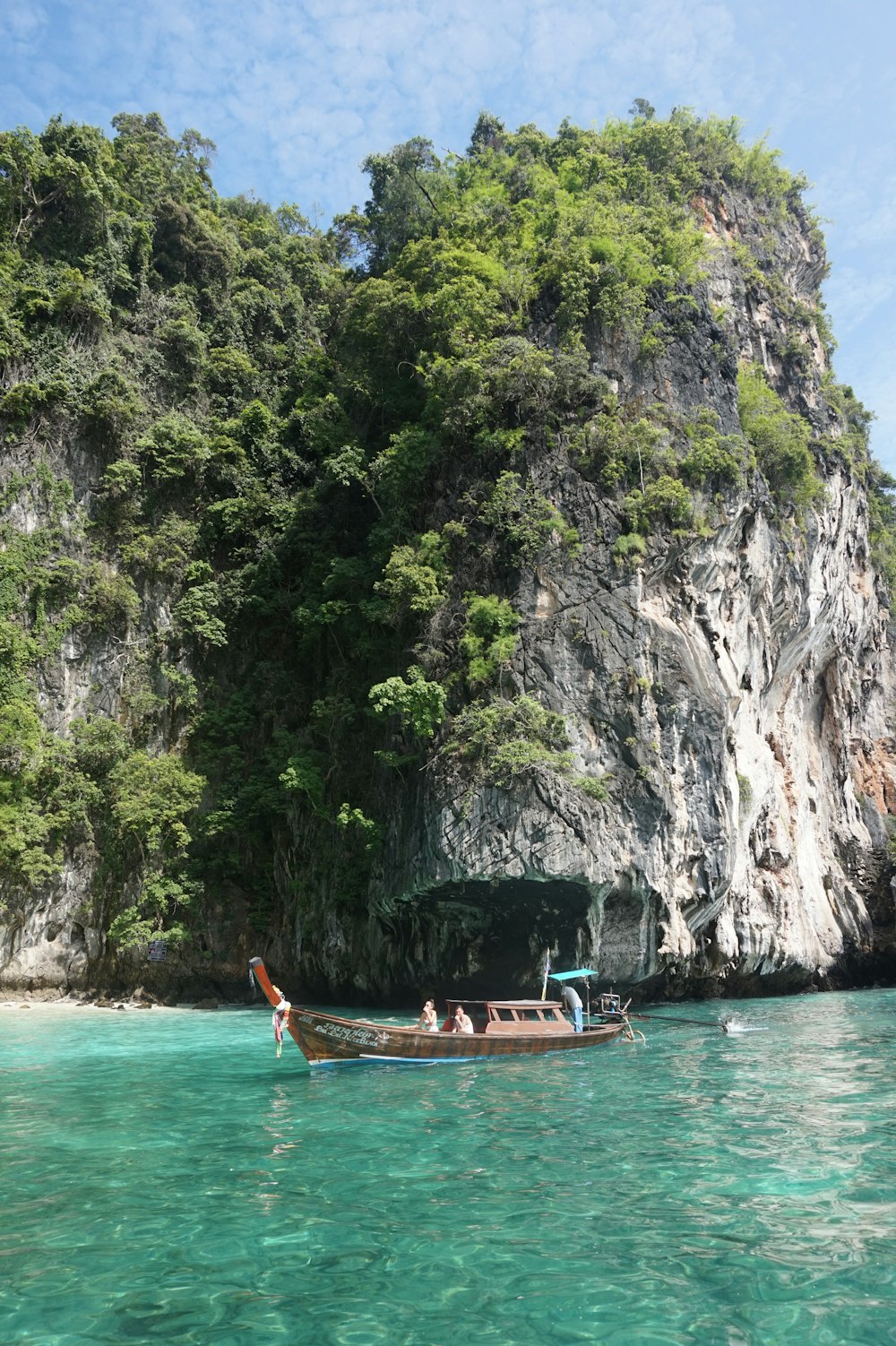 a boat in the water by a cliff