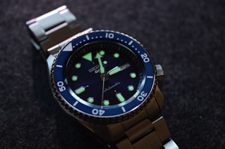 Close-up of a sleek dive watch with a black bezel and luminous markers resting on a textured surface