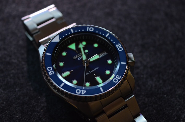 Close-up of a sleek dive watch with a black bezel and luminous markers resting on a textured surface