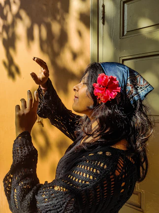 A model gracefully draped in a vibrant, handwoven Turkish scarf against a sunlit stone wall.
