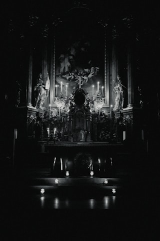 A shadowed altar adorned with glowing blood-red sigils and antique gold candles flickering against a charcoal backdrop.