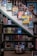 A cozy, well-organized bookstore corner with books displayed on shelves and steps. Colorful children's books are propped up on the stairs, and there is a basket labeled 'Keep the Kids Busy Books' filled with additional titles. The wooden floors and bookshelves give a warm and inviting atmosphere.