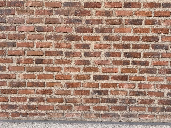 Rows of red bricks with varying shades, neatly arranged in a horizontal pattern, set against a light mortar.