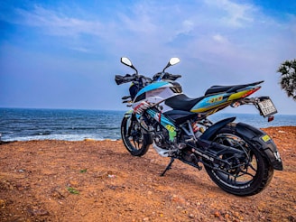A winding coastal road with a classic cruiser motorcycle parked beside a cliff overlooking the ocean.
