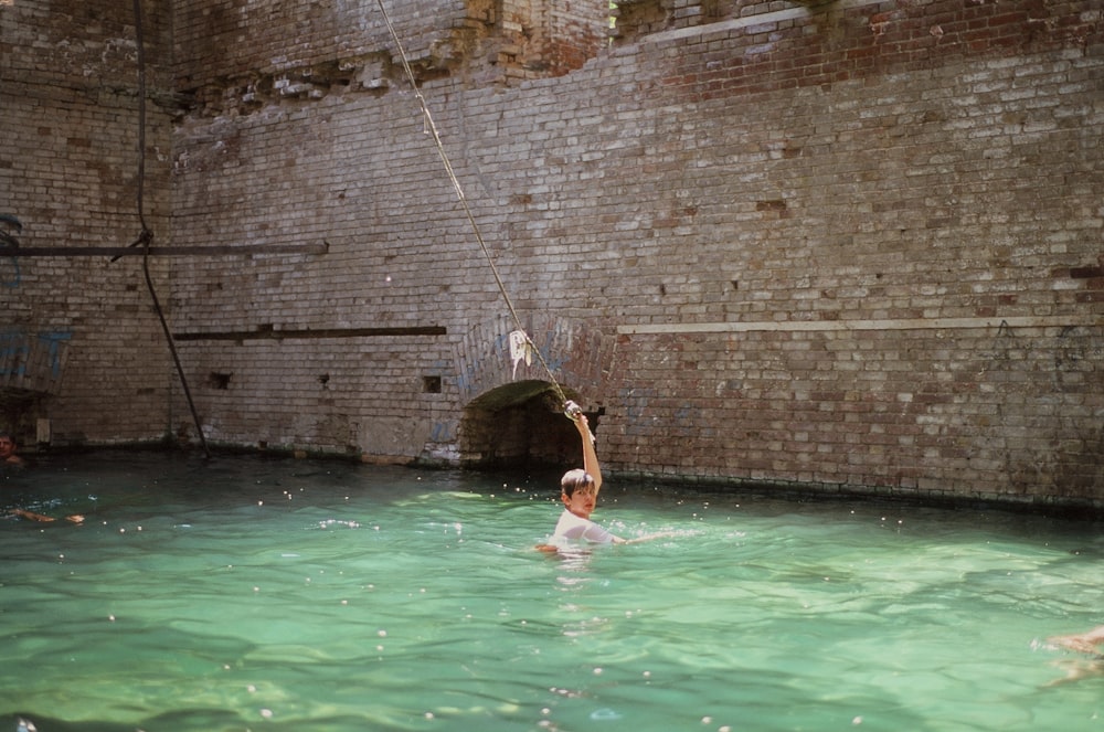 a person in a pool with a bird on the head