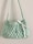 A small, handmade crochet bag with a textured pattern and a single strap. The bag features a decorative white ribbon tied into a bow on the front.