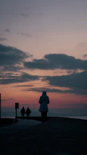 A peaceful sunset view over a pilgrimage site with pilgrims walking along a stone path.