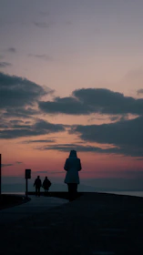 A peaceful sunset view over a pilgrimage site with pilgrims walking along a stone path.