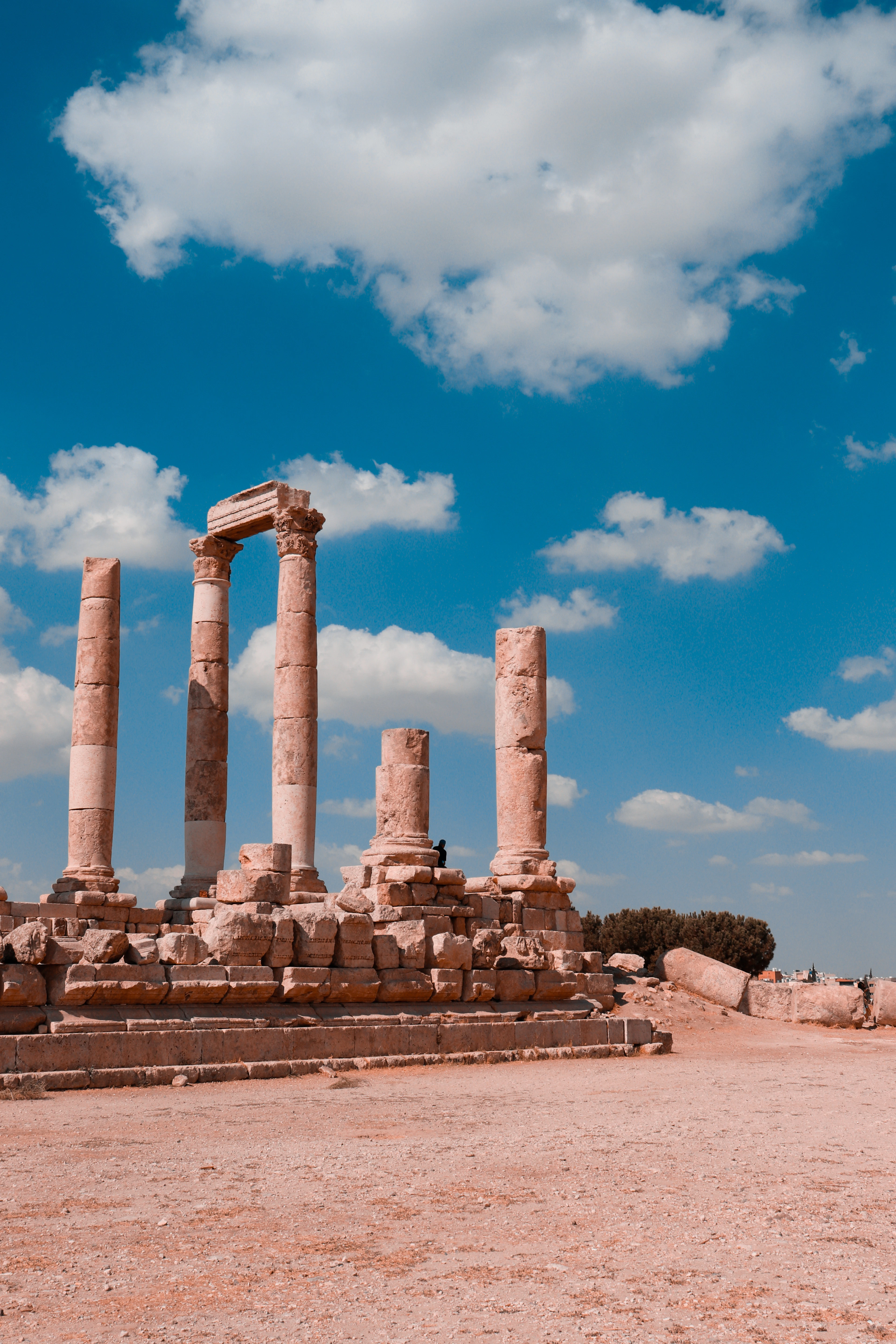 The standing columns of the Temple of Hercules at Amman's Citadel under a blue sky with clouds.
