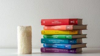 A stack of colorful books with pastel rainbow covers arranged on a wooden table.