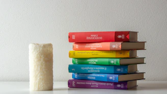 A vibrant stack of colorful books with a backdrop of Singapore’s skyline at sunset.