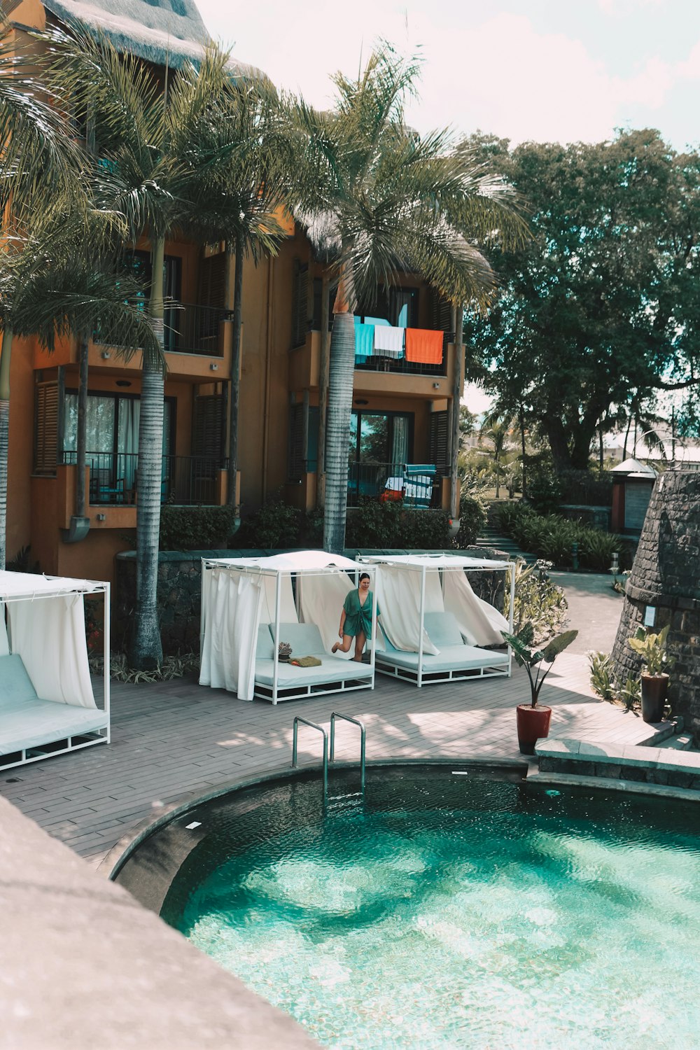 a pool with a table and chairs by a building with palm trees