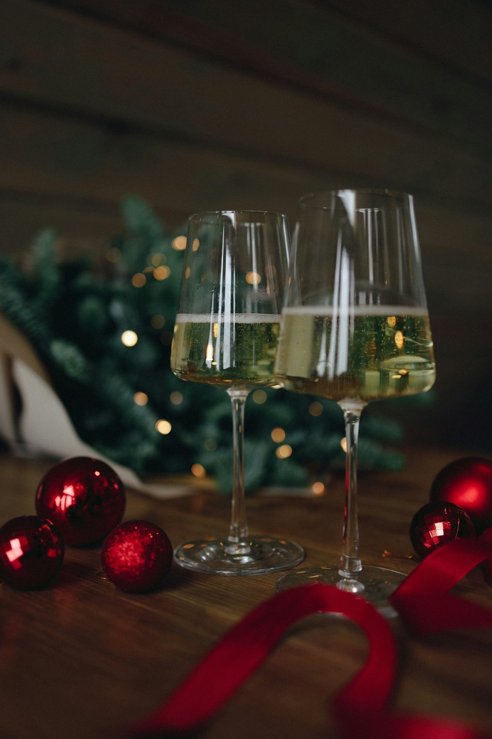 a couple of wine glasses on a table with christmas lights