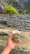Hands of a lithologist examining rock samples beside a steaming cup of coffee.