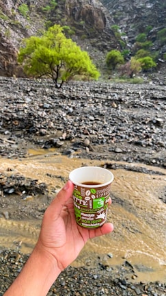 Hands holding a hot beverage in a branded Ecocup Nevşehir cardboard cup outdoors