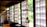 An interior with traditional Japanese sliding doors made of wood and frosted glass or paper, letting in ample natural light. Hanging close to the camera is a glass kerosene lamp, adding a rustic touch to the serene environment. The room has wooden floors and simple furniture, reflecting a minimalist aesthetic.