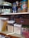 A pantry with organized items including jars of peanut butter, canned sardines, dry pasta, rice, sugar, and various packaged goods. A spice carousel with boxed and canned foods is also visible.