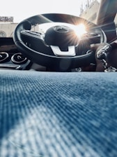 Close-up photo of a car steering wheel with hands ready to drive on a sunny day.