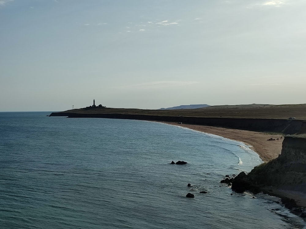 a beach with a lighthouse in the distance