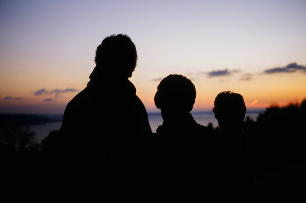 silhouette of people standing in front of a sunset