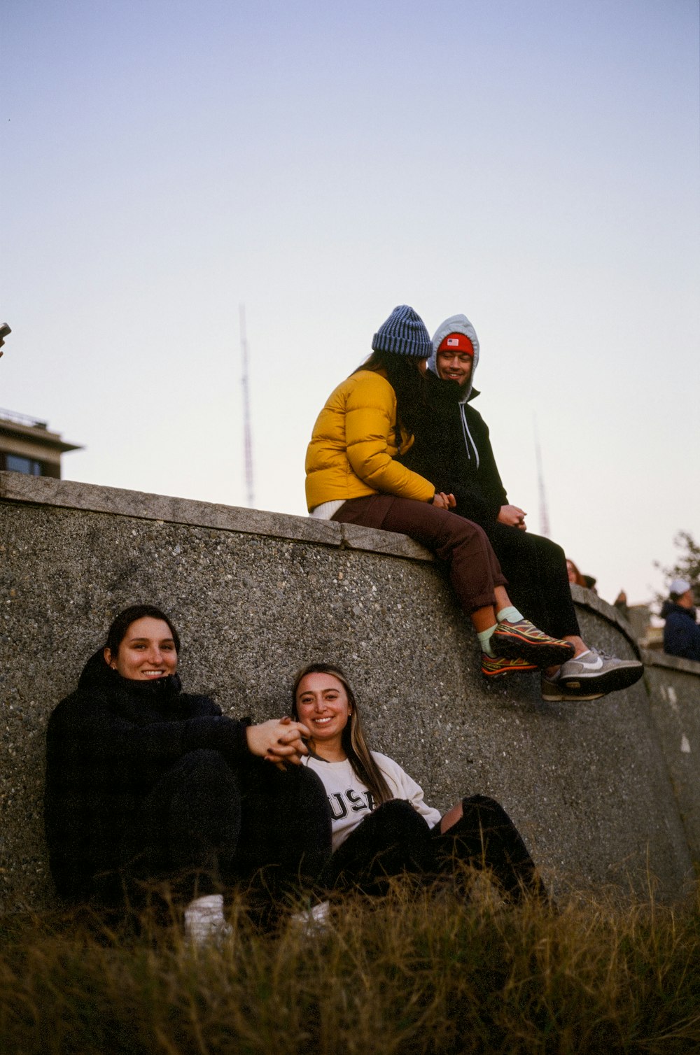 a group of people sitting on a stone wall