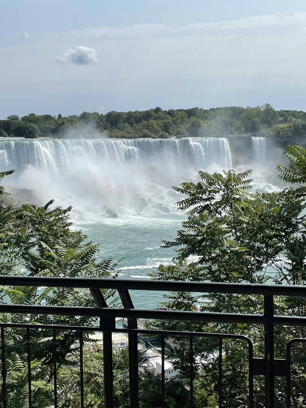 a waterfall with trees and a railing