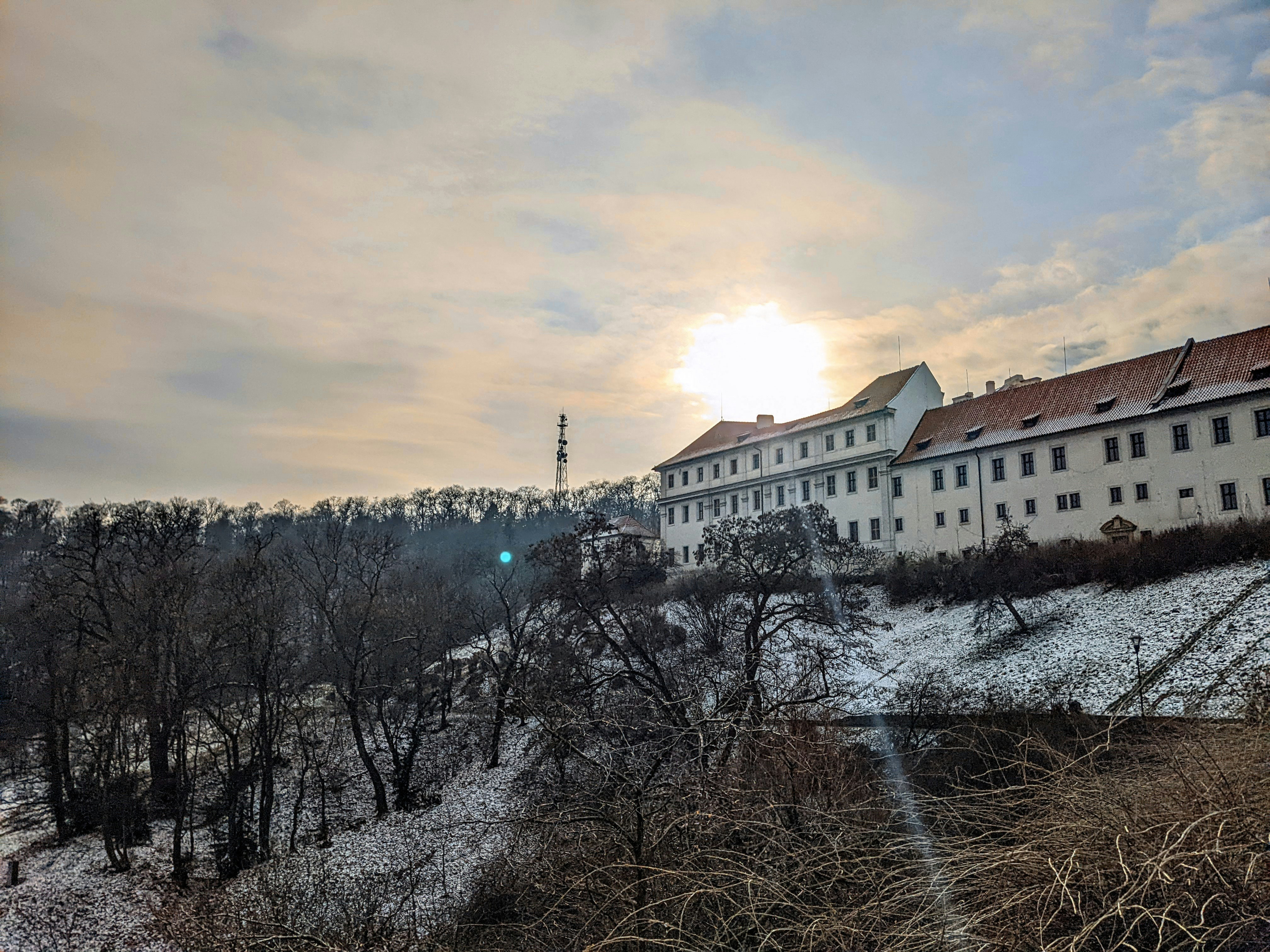 A building with trees in front of it and a snowy field in front