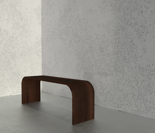 Elegant wooden bench with a smooth finish placed against a white wall.